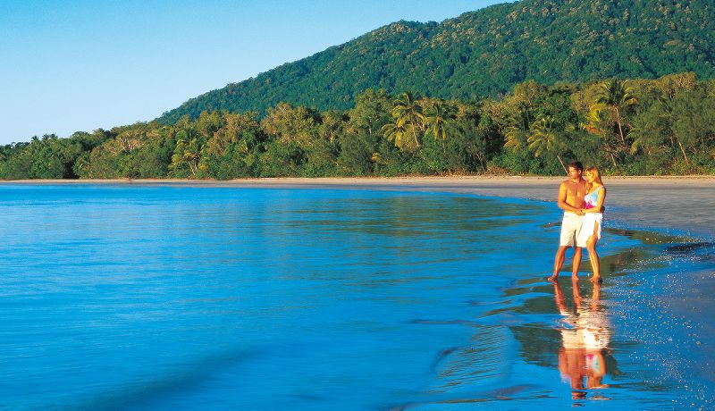 Couple standing on the shoreline where the Daintree Rainforest meets the beach at Cape Tribulation
