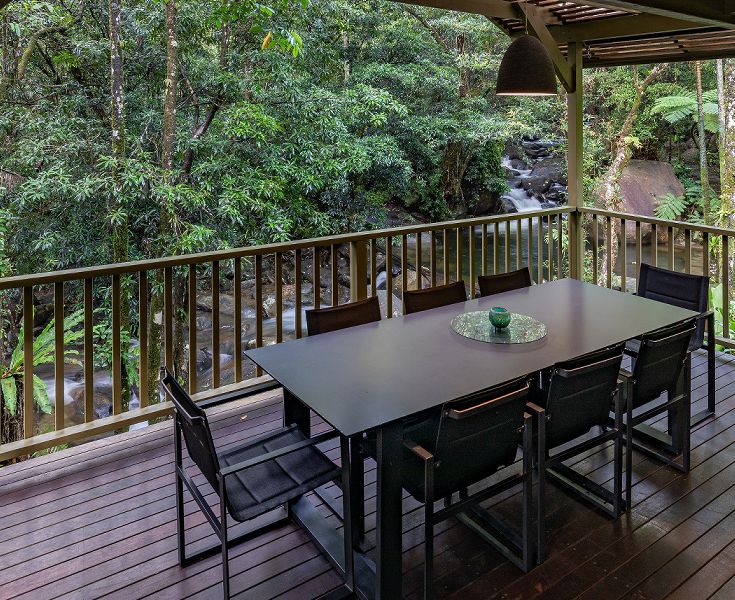Al fresco dining deck with 270-degree views of the private mountain stream and natural waterfalls at Daintree Secrets