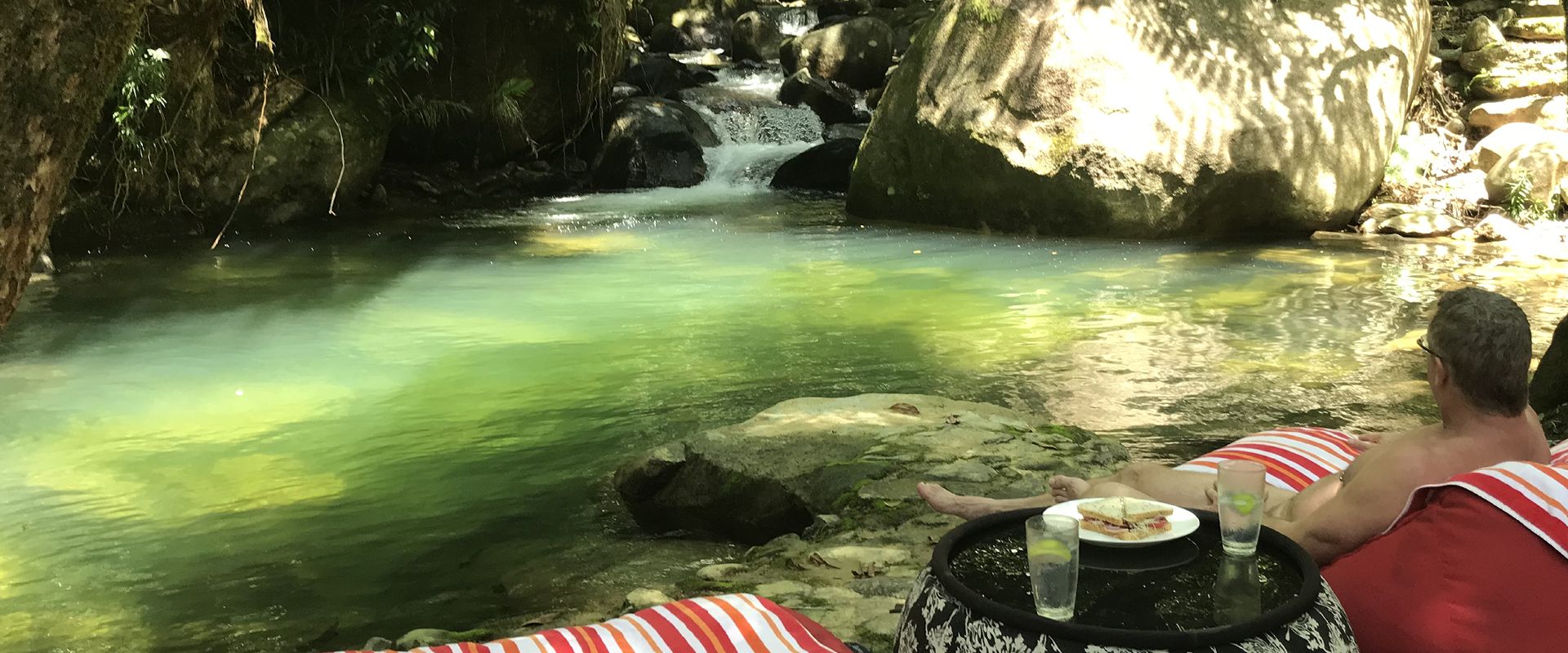Guests enjoying lunch in bean bags by the private swimming hole and waterfalls at Daintree Secrets Rainforest Sanctuary.