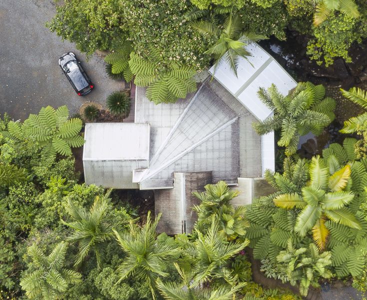 Aerial view of the Daintree Secrets holiday home rooftops and flat driveway parking area nestled deep in the tropical forest canopy