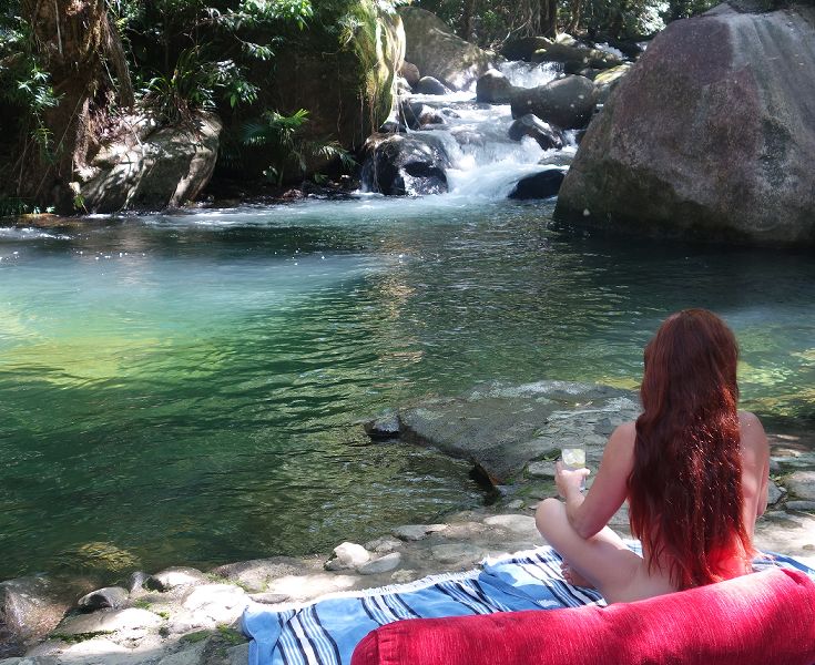 Guest enjoying a relaxing afternoon lounging directly alongside the clear freshwater mountain stream swimming hole