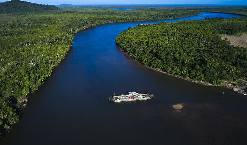 Aerial perspective of the wide Daintree River winding out to the Coral Sea, bordered by ancient tropical rainforest