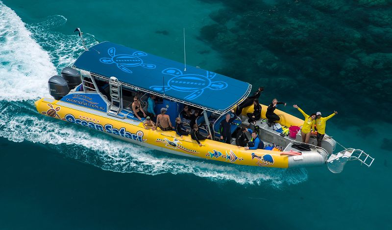 Ocean Safari rigid inflatable boat cruising over the Great Barrier Reef coral reef flats off the Daintree coast