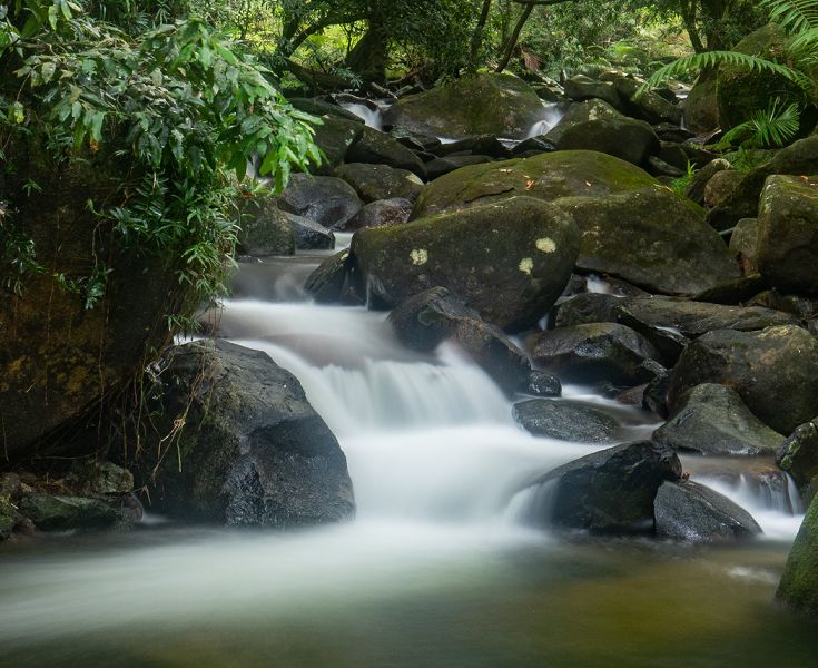 Close-up view of the beautiful natural cascading waterfalls feeding the private swimming hole on the eco retreat grounds