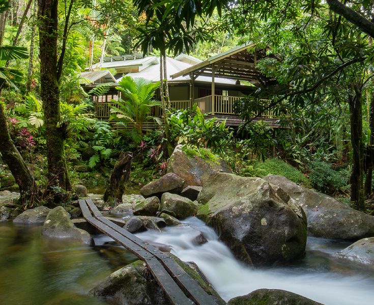 Wooden entry walkway passing directly over the private cascades and freshwater creek towards the main house veranda